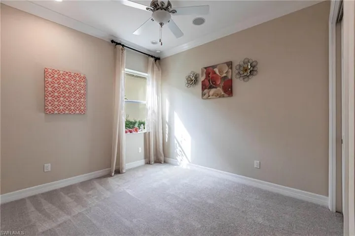 Unfurnished bedroom featuring light carpet, baseboards, a ceiling fan, and crown molding