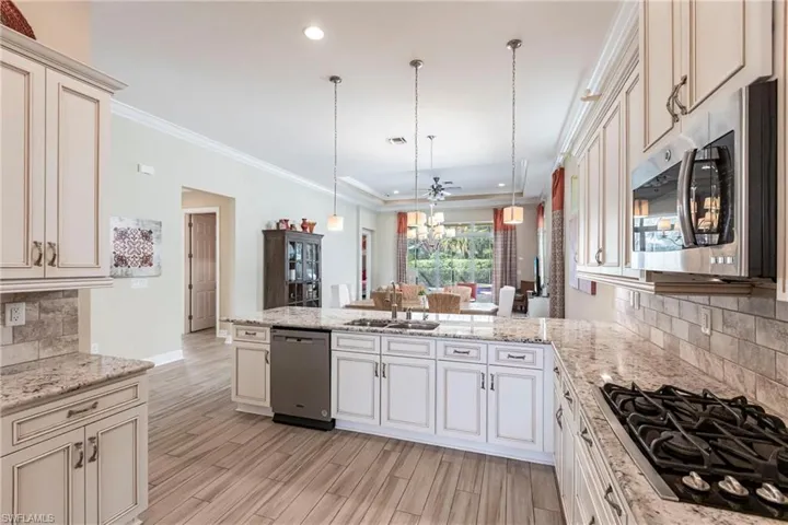 Kitchen featuring a peninsula, stainless steel appliances, a sink, and decorative light fixtures