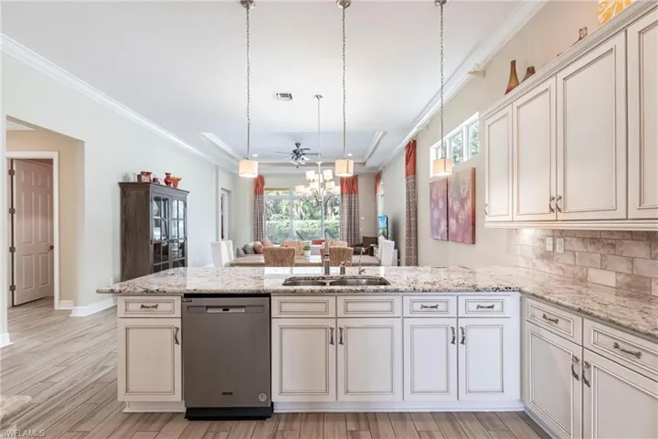 Kitchen with decorative light fixtures, visible vents, stainless steel dishwasher, ornamental molding, and a sink