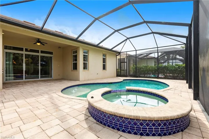 View of pool featuring ceiling fan, a patio area, a lanai, and a pool with connected hot tub