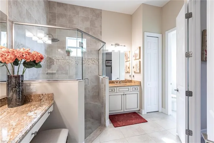 Bathroom featuring a closet, vanity, a shower stall, and tile patterned floors