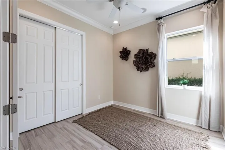 Unfurnished bedroom featuring baseboards, a ceiling fan, ornamental molding, light wood-style floors, and a closet