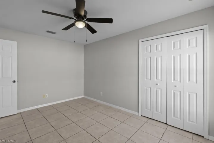 Unfurnished bedroom featuring ceiling fan, light tile patterned flooring, and a closet