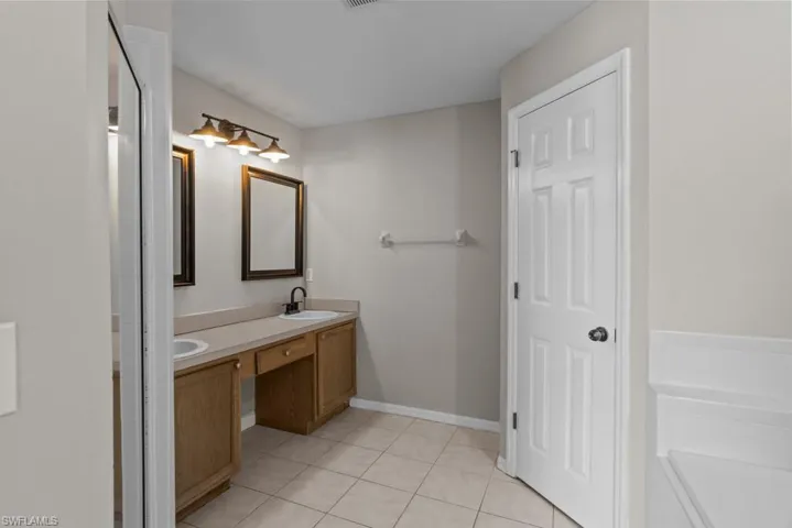 Bathroom with light tile patterned flooring, double vanity, and a stall shower