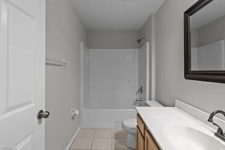 Bathroom with light tile patterned floors, washtub / shower combination, and vanity