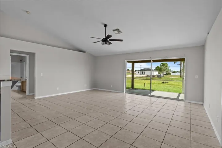 Spare room with light tile patterned floors, vaulted ceiling, and a ceiling fan