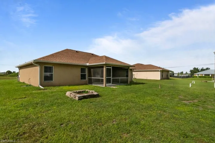 Rear view of house with a lawn, a sunroom, and stucco siding