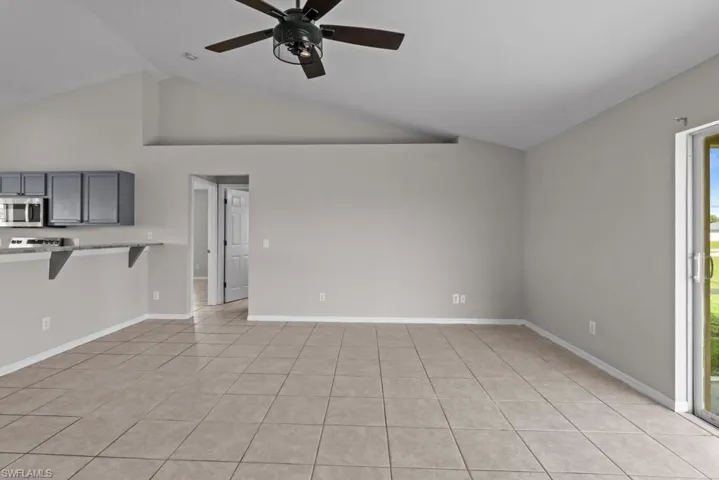 Unfurnished living room with light tile patterned floors, high vaulted ceiling, and ceiling fan