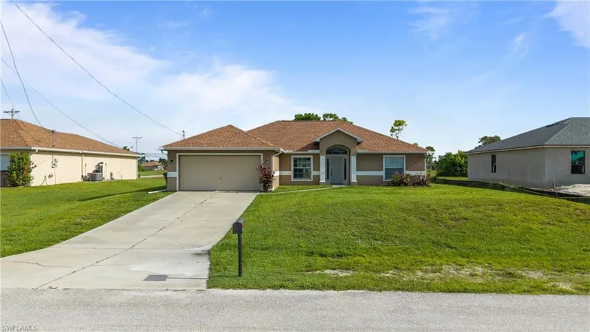 Ranch-style house with concrete driveway, a front yard, stucco siding, and an attached garage
