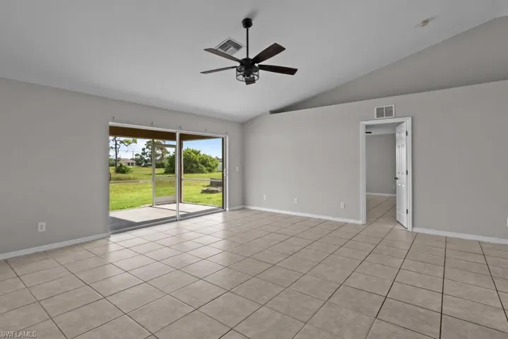 Empty room featuring light tile patterned flooring, a ceiling fan, and high vaulted ceiling
