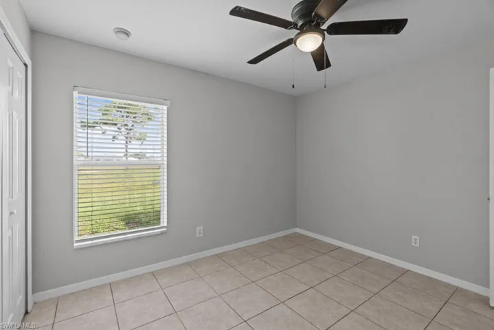 Empty room featuring light tile patterned flooring and ceiling fan