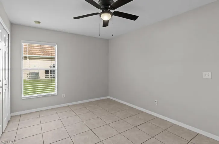 Unfurnished room with light tile patterned floors and ceiling fan