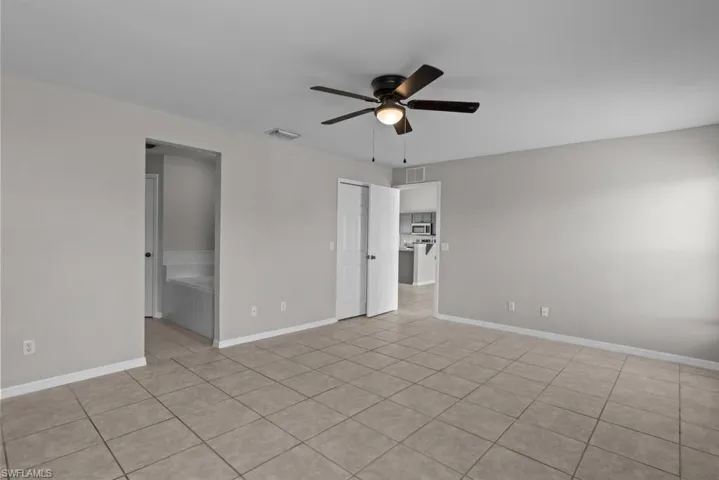 Unfurnished bedroom with light tile patterned floors, a ceiling fan, and connected bathroom