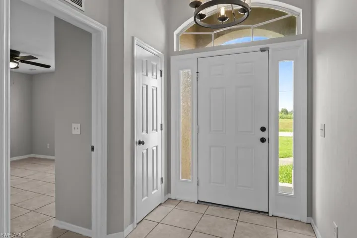 Entryway featuring light tile patterned floors, a ceiling fan, and a chandelier