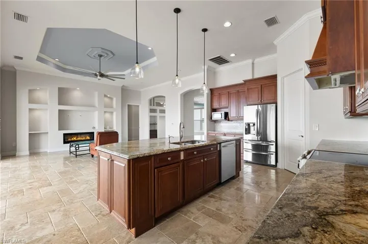 Kitchen with hanging light fixtures, stainless steel appliances, a tray ceiling, and sink