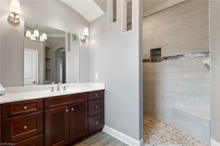 Bathroom featuring wood-type flooring, an inviting chandelier, vanity, and ornamental molding