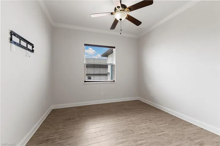 Spare room featuring wood-type flooring, ceiling fan, and crown molding
