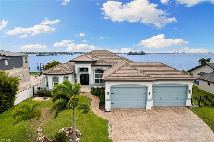 View of front of home with a garage, a water view, and a front yard