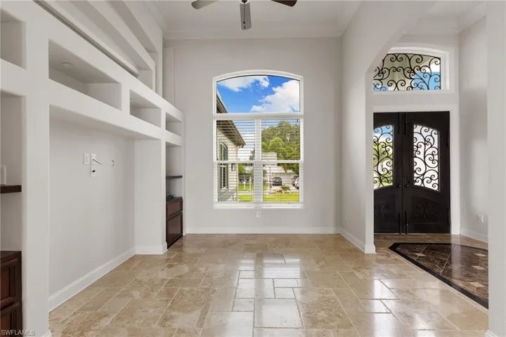 Foyer entrance with crown molding, french doors, ceiling fan, and light tile floors