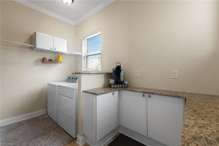 Clothes washing area with ornamental molding, washer and dryer, and cabinets