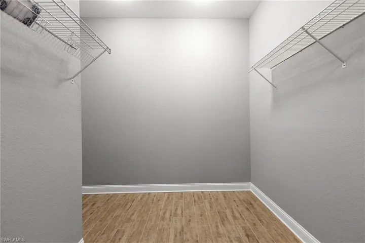 Walk in closet with hardwood / wood-style floors