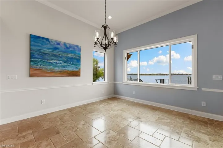 Tiled empty room featuring ornamental molding, a water view, and an inviting chandelier