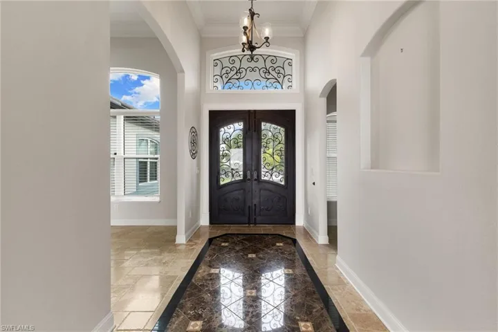 Foyer entrance featuring a notable chandelier, tile flooring, crown molding, and french doors