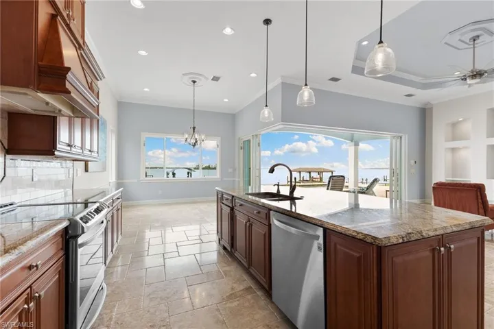 Kitchen featuring dishwasher, range with electric stovetop, an island with sink, sink, and pendant lighting