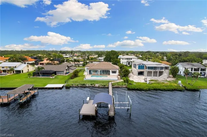 View of dock with a pool, a lawn, and a water view