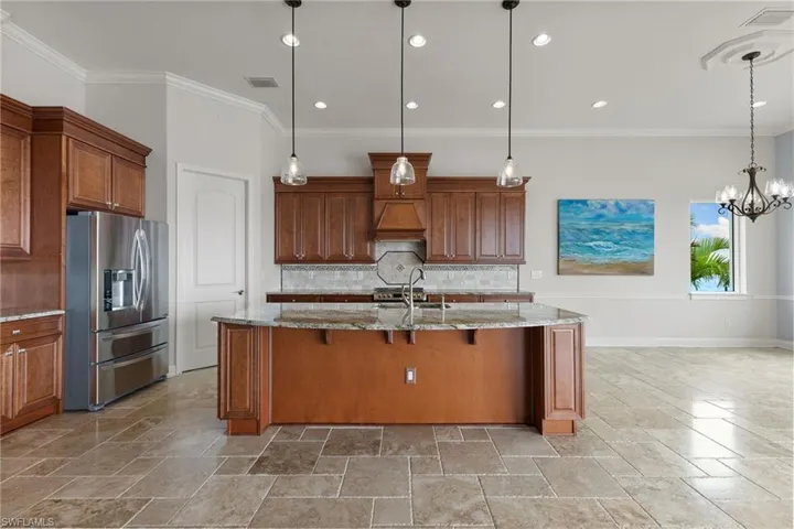 Kitchen featuring decorative light fixtures, light stone countertops, stainless steel fridge with ice dispenser, and backsplash
