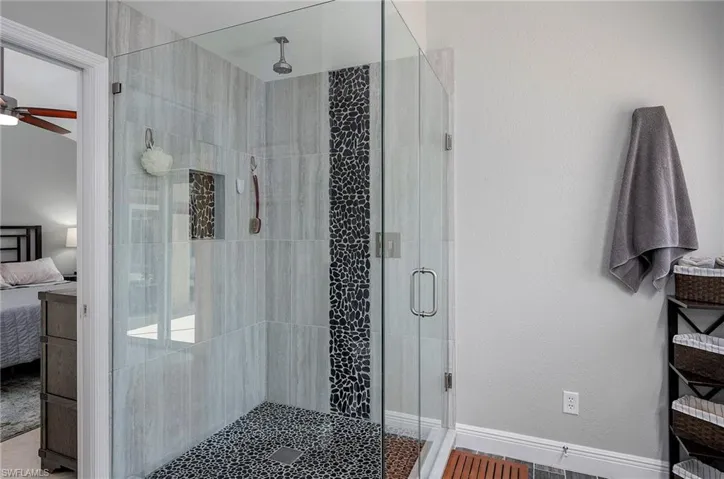 Bathroom featuring ceiling fan and an enclosed shower
