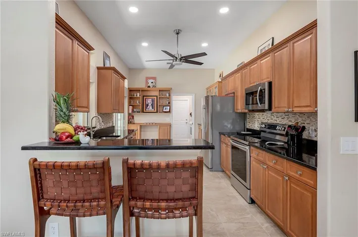 Kitchen with kitchen peninsula, backsplash, ceiling fan, appliances with stainless steel finishes, and sink