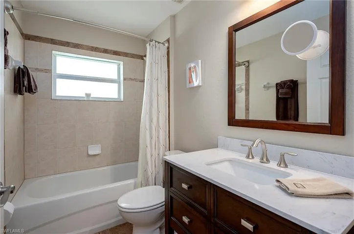 Full bathroom with shower / bath combo with shower curtain, toilet, and vanity
