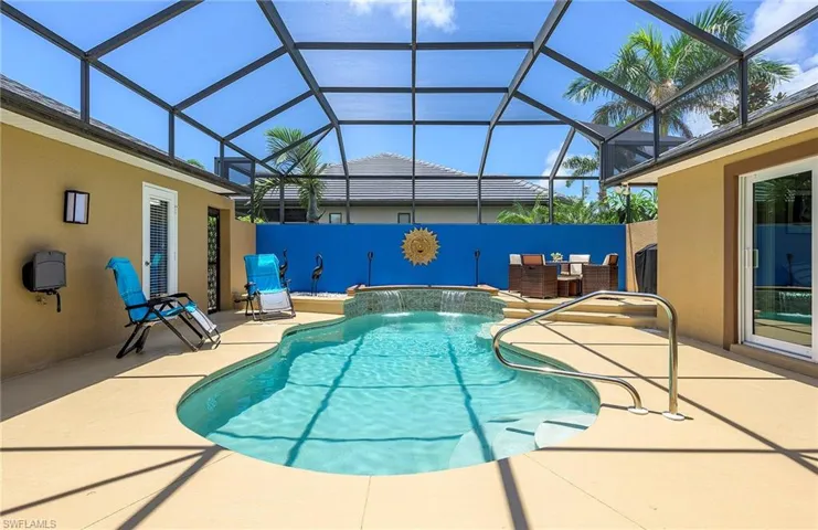 View of swimming pool featuring a patio area, pool water feature, a jacuzzi, and glass enclosure