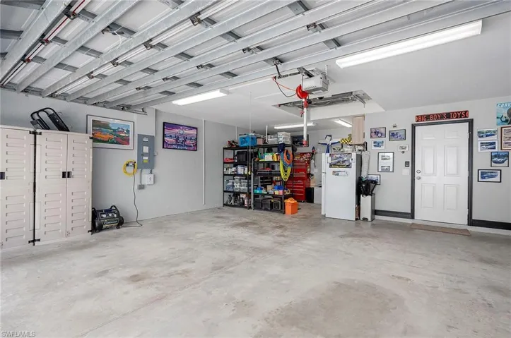 Garage featuring white fridge, electric panel, and a garage door opener