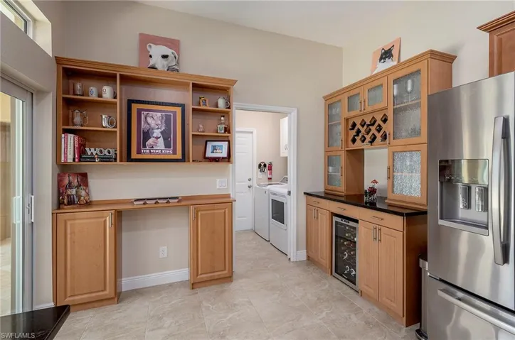 Kitchen featuring separate washer and dryer, stainless steel refrigerator with ice dispenser, light tile patterned floors, and wine cooler