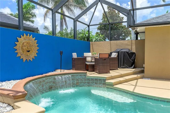 View of pool with area for grilling, pool water feature, a patio area, and a lanai