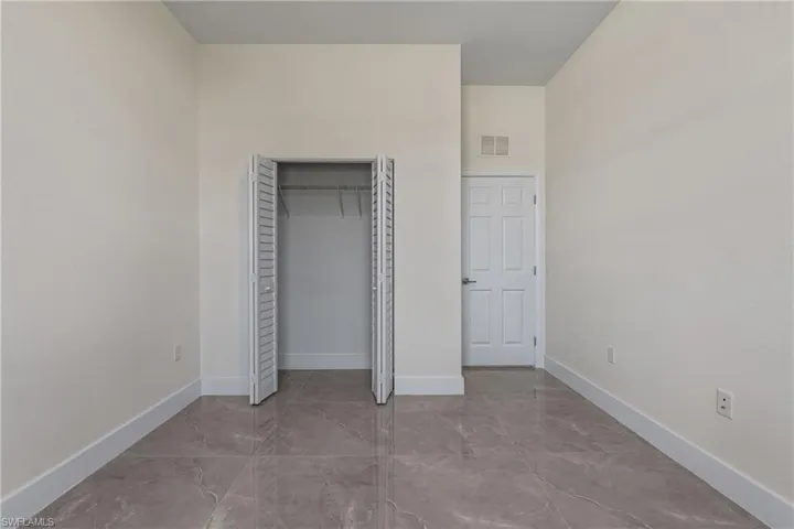 Unfurnished bedroom with a closet and marble tiled floors