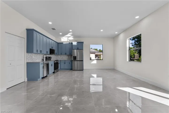 Kitchen featuring appliances with stainless steel finishes, light countertops, light marble finish floors, blue cabinets, and decorative backsplash