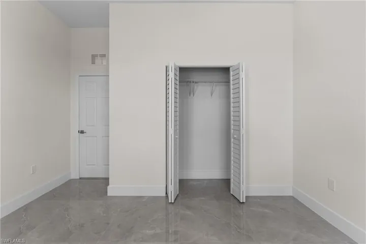 Unfurnished bedroom with a closet and finished concrete flooring
