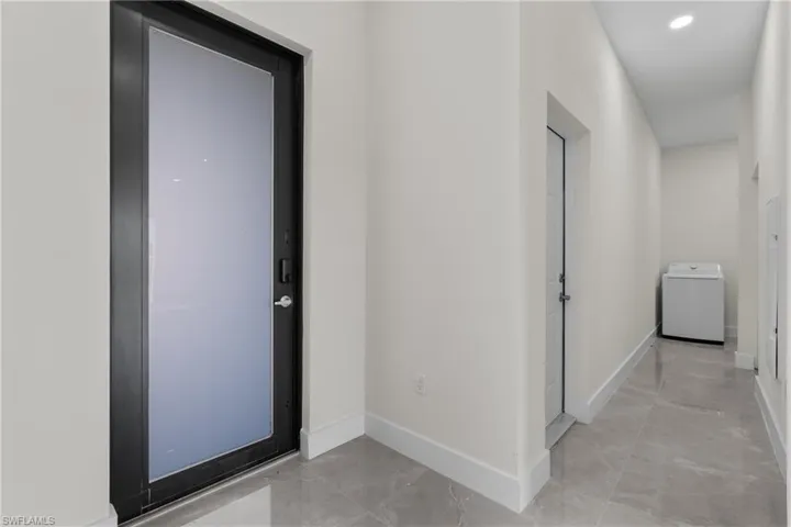 Hall featuring washer / dryer and recessed lighting