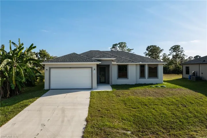 View of front of property featuring concrete driveway, stucco siding, a front lawn, and a garage