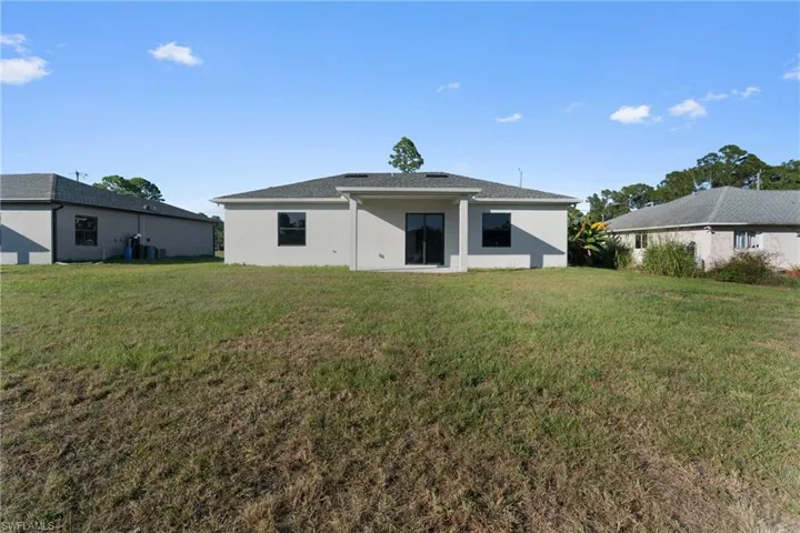 Rear view of house with a yard, a patio, and stucco siding