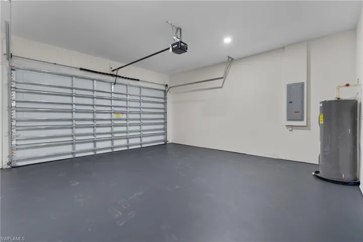 Garage featuring water heater, electric panel, and a garage door opener