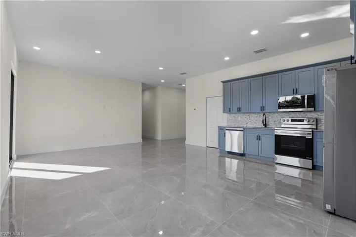 Kitchen with stainless steel appliances, recessed lighting, backsplash, light marble finish floors, and open floor plan