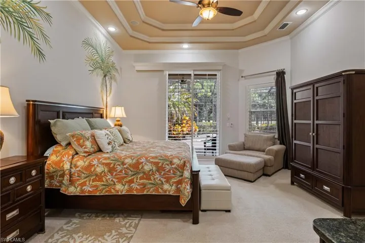 Carpeted bedroom with access to outside, ceiling fan, a raised ceiling, and ornamental molding