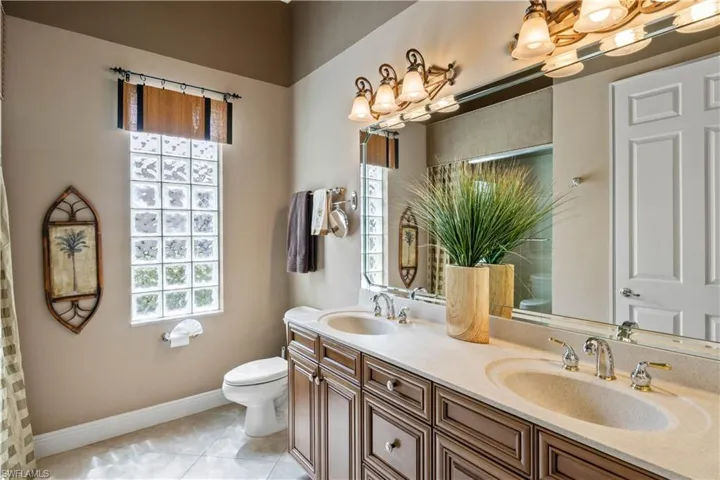 Bathroom featuring dual vanity, toilet, and tile patterned flooring