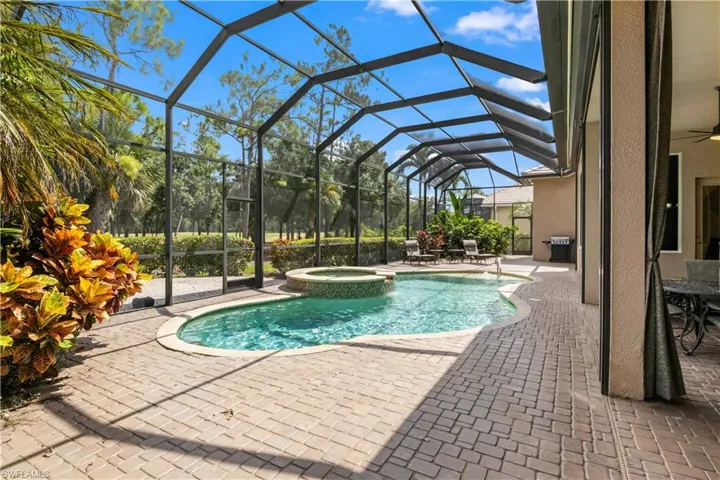 View of pool featuring ceiling fan, a patio, an in ground hot tub, grilling area, and glass enclosure