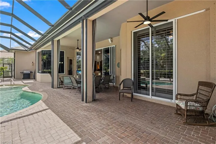 View of patio featuring ceiling fan, a grill, and glass enclosure