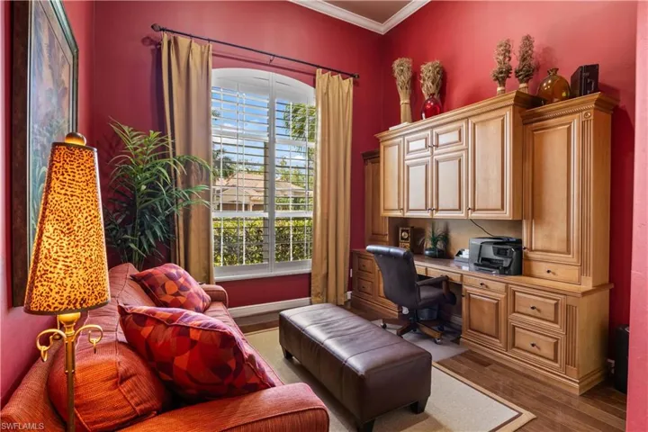 Home office featuring built in desk, wood-type flooring, and ornamental molding